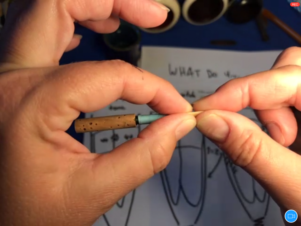 Hands adjusting opening and tension of an oboe reed